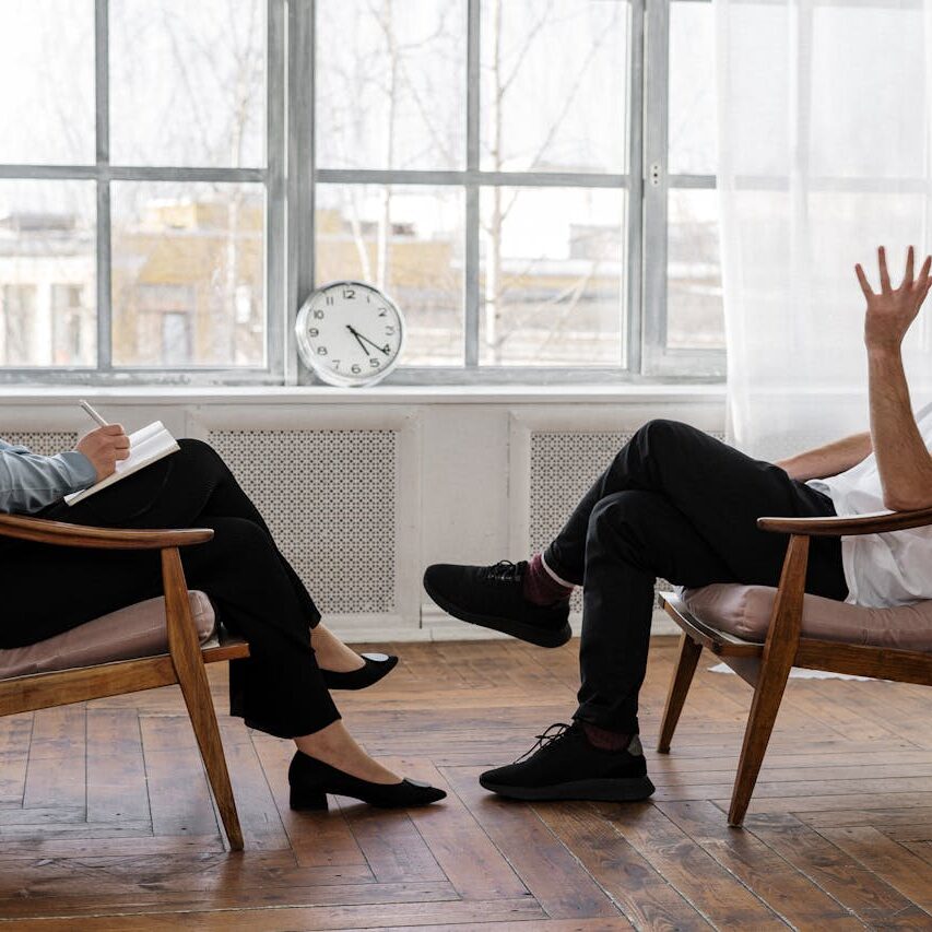 A therapist engaging in a counseling session with a male patient to support mental health.